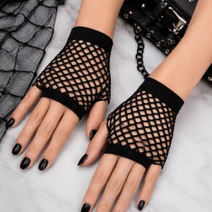 Pode incluir: Um par de luvas pretas sem dedos de rede com um padr&atilde;o de malha larga em forma de diamante e punhos el&aacute;sticos pretos s&oacute;lidos nos pulsos e n&oacute;s dos dedos. As luvas s&atilde;o feitas de um material leve e flex&iacute;vel com uma trama consistente.