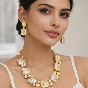 Può includere: Un set di collana e orecchini dorati. La collana presenta grandi pietre quadrate bianche sporco incastonate in montature dorate, intervallate da pietre più piccole, rotonde e trasparenti. Gli orecchini hanno un design simile.