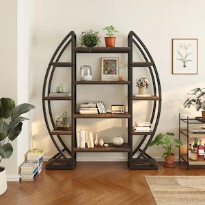 Puede incluir: Una estantería de metal negro y madera con diseño ovalado. Los estantes están llenos de libros, plantas y objetos decorativos. La estantería es una solución de almacenamiento elegante para cualquier habitación.