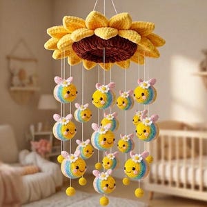 May include: A handmade crochet baby mobile featuring a large yellow sunflower with a brown center. Below, smiling bee figures in yellow, blue, and rainbow colors hang from the sunflower. The mobile is designed for a nursery.