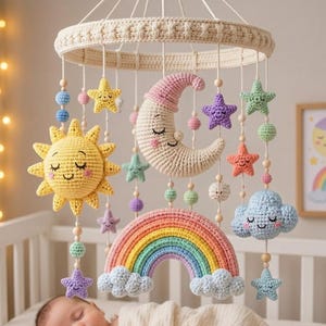 Può includere: Una giostrina per culla all'uncinetto con una luna crescente color crema dal volto addormentato, un sole giallo brillante, un arcobaleno multicolore e varie stelle e nuvole color pastello sospese a una struttura circolare color crema.