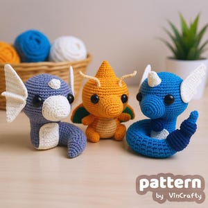 May include: Three handmade crochet figures in blue, orange, and blue-green. The figures have large eyes and white accents. The orange figure has green wings. The blue figure is coiled. The text "pattern by VinCrafty" is at the bottom.