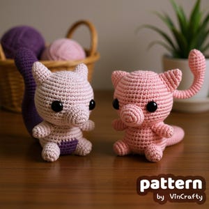 May include: Two crocheted figures, one light pink and one pink, with black eyes, sit side-by-side. The light pink figure has a purple accent. A basket with yarn and a plant are in the background. The text "pattern by VinCrafty" is in the lower right corner.