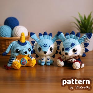 Puede incluir: Tres criaturas hechas a mano con ganchillo en azul, blanco y amarillo. Las criaturas tienen diseños únicos, incluyendo cuernos, alas y elementos decorativos. La imagen incluye el texto "pattern by VinCrafty".