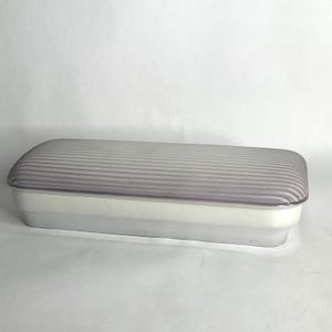 May include: A rectangular, two-tone container with a clear, ribbed lid. The base is white, and the lid is a translucent gray. The container has rounded edges and a simple, clean design. The container is likely for storage.