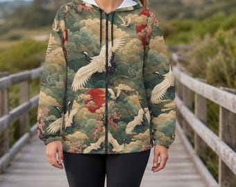 May include: A zip-up hooded jacket featuring a repeating pattern of white cranes in flight, red suns, and green clouds. The jacket has long sleeves, a front zip fastening, and a white inner lining, paired with solid black leggings and white trainers.