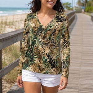 May include: A long-sleeve V-neck top featuring a multi-colored animal and botanical print in shades of green, brown, and black, paired with solid white shorts. The top has a fitted silhouette and the shorts are plain with a clean hemline.