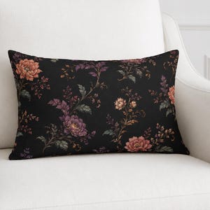 May include: A rectangular throw pillow featuring a black background with a repeating floral pattern in shades of muted orange, deep purple, and dark green. The design displays various blooming flowers and leafy stems across the entire surface.