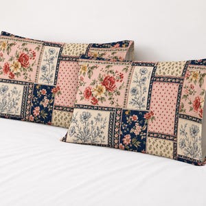May include: Two rectangular pillowcases featuring a patchwork design of floral and polka dot patterns. The fabric displays a color palette of pink, navy blue, cream, and red, with detailed illustrations of roses and wildflowers in square sections.