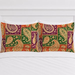Puede incluir: Dos fundas de almohada rectangulares con un diseño de patchwork de patrones de cachemira y flores en tonos vibrantes de naranja, morado intenso y verde bosque. La tela muestra un motivo repetitivo de formas de lágrima y pequeñas flores.
