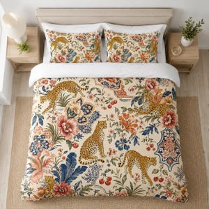 May include: A beige comforter set with a floral and leopard print. The bedding features large pink and orange flowers, blue leaves, and several leopards. Two matching pillowcases are visible on the bed.