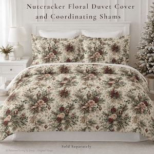May include: A Nutcracker Floral Duvet Cover and Coordinating Shams featuring a cream-colored fabric with a repeating pattern of nutcrackers, red roses, green pine branches, ribbons, and ornaments. The text reads Nutcracker Floral Duvet Cover and Coordinating Shams.