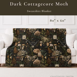 May include: A sweatshirt blanket measuring 203 cm by 152 cm, featuring a dark, repeating pattern of moths, mushrooms, ferns, and hydrangea flowers. The design includes small rectangular frames and botanical elements on a black background.