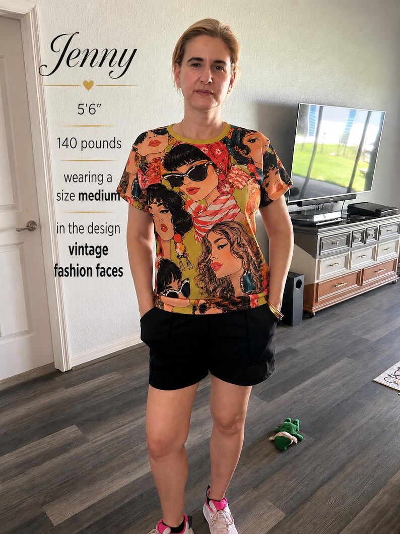May include: A short-sleeved crew neck t-shirt featuring a repeating graphic print of stylized faces with sunglasses and headscarves in shades of olive green, orange, and black, paired with solid black shorts.