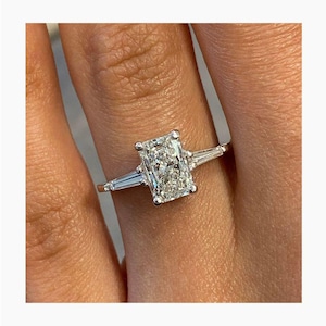 Anillo de tres diamantes talla princesa con laterales de diamantes talla baguette.