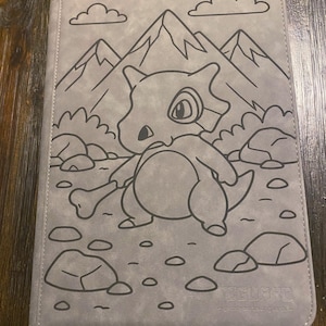 May include: Grey card binder featuring a Cubone illustration with mountains and clouds. The Cubone is holding a bone. The binder has the text "Feel Guard" at the bottom.