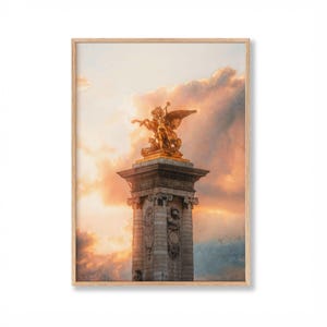 May include: Framed print featuring a golden statue atop a stone column against a sunset sky. The statue depicts a winged figure riding a horse. The artwork is set in a wooden frame, evoking a sense of classic elegance.