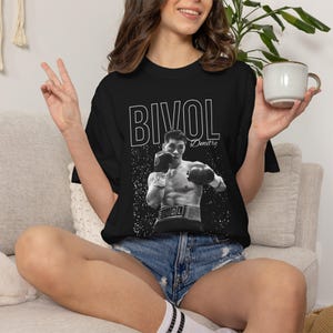May include: A black short-sleeve t-shirt featuring a white graphic print of a boxer in action. The text BIVOL is printed in large capital letters above the image, with the name Dmitry written in script to the right of the boxer's head.