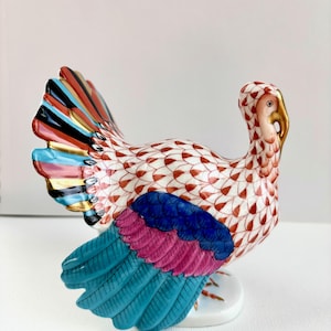 May include: A white ceramic mug with a black handle and the text "But First, Coffee" in a bold, black font. The mug is set against a blurred background, suggesting a cozy setting.