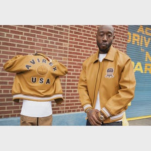 May include: Mustard-colored leather jacket with the text "AVIREX USA" on the back and a patch on the front. The jacket has a collared neckline, ribbed cuffs, and a white and tan striped hem.