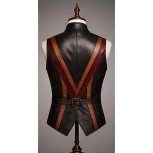 Puede incluir: Chaleco de cuero negro con rayas marrones y burdeos. El chaleco tiene un cintur&oacute;n con hebilla en la cintura y se exhibe en un maniqu&iacute;. Una prenda elegante.