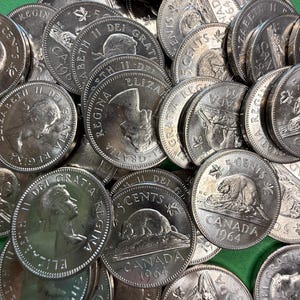 May include: A collection of Canadian coins, including 5-cent pieces from 1964, featuring a beaver. The coins are silver in color and display the profile of Queen Elizabeth II and the inscription "ELIZABETH II DEI GRATIA REGINA".