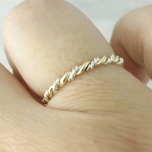 May include: A thin gold and silver twisted band ring.