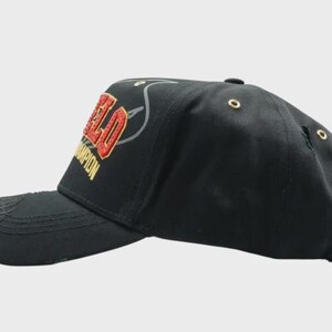May include: Black baseball cap with the word "FIELD" in red and gold embroidery. The word "CHAMPION" is embroidered in gold. The cap has a curved brim and a distressed look.