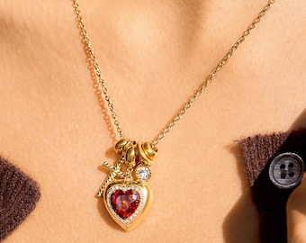 Collana con croce a forma di cuore in oro e rubino, composta da più perline.