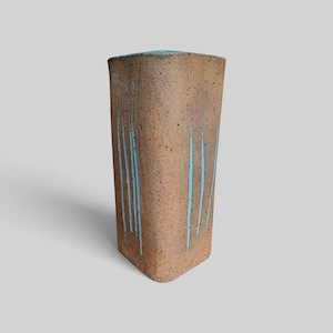 Peut inclure: Un vase en céramique triangulaire et haut, doté d'une surface texturée tachetée dans des tons beige et brun. L'extérieur présente des coulures de glaçure bleu clair verticales descendant du bord supérieur, contrastant avec l'argile tachetée.
