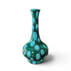 Peut inclure: Un vase en céramique avec une base arrondie et un long col fin. Le vase est émaillé en bleu sarcelle et vert foncé, avec un motif de gouttes. Le vase a une finition brillante et repose sur une petite base circulaire. Hauteur d'environ 25 cm.