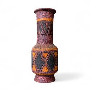 Peut inclure: Un vase texturé de couleur brun rougeâtre, orné de motifs géométriques orange et noirs. Le vase a une base large et un sommet évasé. Il est idéal pour exposer des fleurs ou comme pièce décorative. Les mesures du vase sont en centimètres.