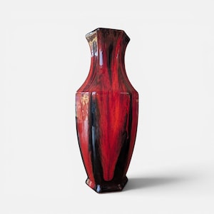 Peut inclure: Un grand vase en céramique élancé doté d'une finition brillante avec un motif marbré tourbillonnant spectaculaire dans des tons de noir profond et de rouge vif. Le vase présente un col étroit, un bord évasé et un corps arrondi.