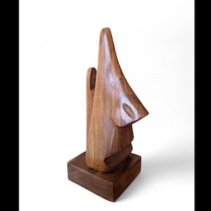 Peut inclure: Sculpture en bois représentant un nez, fabriquée à partir de bois aux tons chauds. La sculpture est montée sur une base carrée. Le design présente une narine détaillée et une finition lisse et polie.