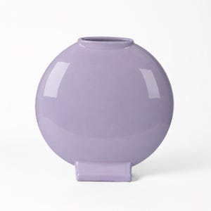 Peut inclure: Un vase sphérique de couleur lavande, avec une base rectangulaire plate. Le vase a une finition brillante et une ouverture circulaire. Le design est moderne et minimaliste.