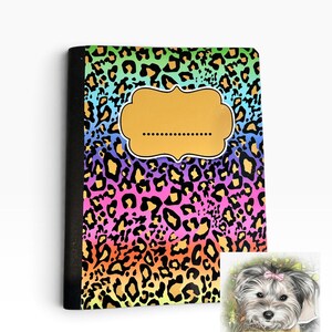 May include: A notebook with a vibrant rainbow gradient background featuring a black leopard print pattern. A solid gold-colored label with a dotted line sits in the center. A small square insert shows a dog illustration with the text Josie Leigh Creations.