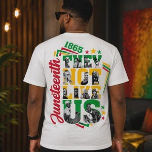 Könnte beinhalten: Ein weißes kurzärmeliges T-Shirt mit einer Grafik auf der Rückseite, die den Text "Juneteenth 1865" und "THEY NOT LIKE US" in Rot, Gelb und Grün zeigt. Das Design enthält eine Collage aus schwarz-weißen Porträts historischer Persönlichkeiten.