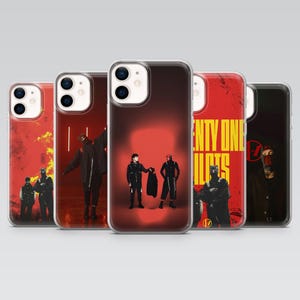 Peut inclure: Cinq coques de smartphone transparentes présentant diverses images du groupe Twenty One Pilots. Les designs incluent des arrière-plans rouges, des silhouettes de deux personnages en tenues noires et le texte jaune TWENTY ONE PILOTS.