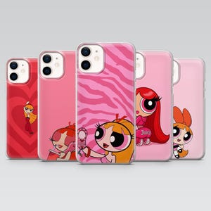 May include: A collection of pink phone cases featuring cartoon characters. Designs include a heart, a zebra print, and various Powerpuff Girls characters. The cases are made of a clear, protective material.