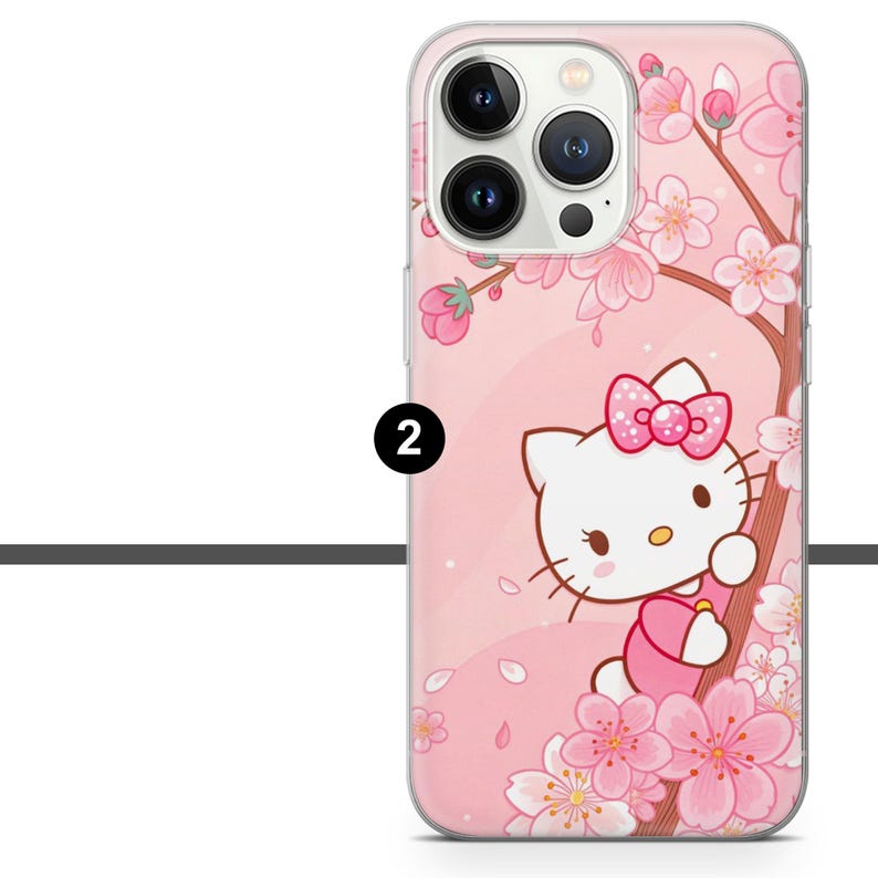 May include: Pink phone case featuring a Hello Kitty design with a pink bow, surrounded by cherry blossom branches and flowers. The case has a clear border and a number 2 printed on the side.