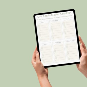 Könnte beinhalten: Ein schwarzes Tablet mit einer "Life Admin Master Checklist" mit Abschnitten für Zuhause, Kinder/Schule, Gesundheit, Arbeit, Geld/Rechnungen und Tiere/Saisonales. Das Tablet wird von zwei Händen vor einem hellgrünen Hintergrund gehalten.