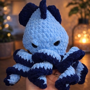 May include: A handmade, light blue and navy blue crocheted octopus plush toy. The octopus has dark eyes and a textured, soft appearance. The tentacles are a darker blue with light blue accents. The toy is designed to be a cuddly, decorative item.