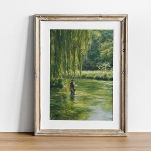 Può includere: Stampa artistica incorniciata di una serena scena fluviale. Una persona pesca a mosca nell'acqua limpida, circondata da un rigoglioso fogliame verde e un salice piangente. L'opera d'arte è presentata in una cornice di legno rustica e dai toni chiari.