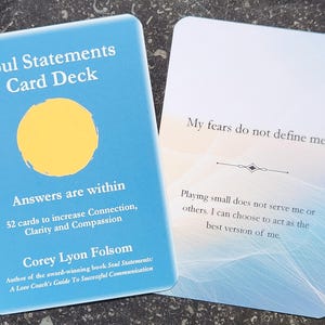 May include: Two rectangular cards from the Soul Statements Card Deck. The blue card features a yellow circle, the text Soul Statements Card Deck, Answers are within, 52 cards to increase Connection, Clarity and Compassion, and Corey Lyon Folsom.