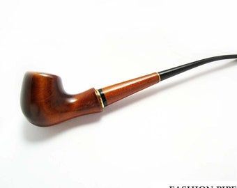 May include: A traditional tobacco pipe with a curved, black stem and a polished, brown wooden bowl. The pipe has a gold-coloured band at the joint and is set against a white background. The text "FASHION PIPES" is visible at the bottom.