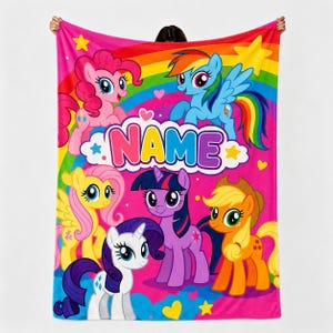 Può includere: Una coperta in pile rosa vivace con un arcobaleno colorato e sei personaggi di My Little Pony, tra cui Pinkie Pie, Rainbow Dash, Fluttershy, Twilight Sparkle, Rarity e Applejack. La parola NAME è stampata in grandi lettere multicolori.