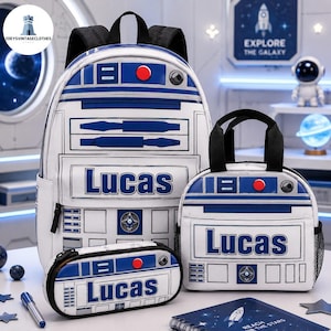 May include: A white backpack, lunch bag, and pencil case set featuring a blue and white robot-inspired graphic design. Each item displays the name Lucas in bold blue lettering, along with red and blue mechanical details and black straps.