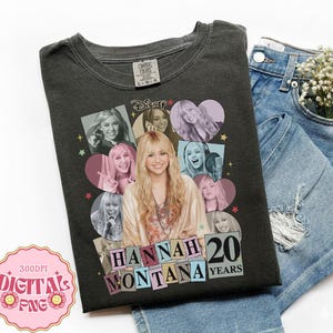 May include: Dark gray t-shirt featuring a collage of images of Hannah Montana, with the text "HANNAH MONTANA 20 YEARS". The shirt is paired with blue denim shorts. The shirt has a Disney logo.