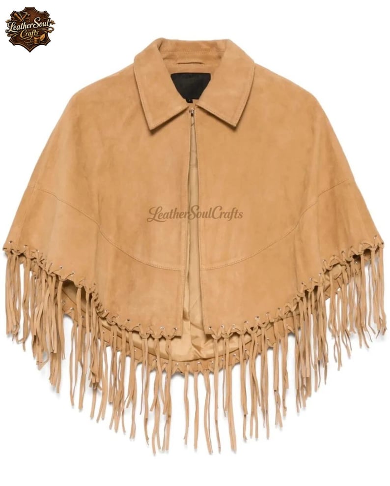 May include: A tan suede cape featuring a pointed collar, a central zipper closure, and long fringe detailing along the bottom hem. The garment includes a horizontal seam across the chest and is branded with the text Leather Soul Crafts.