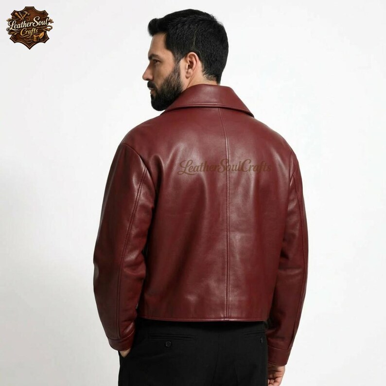 May include: A burgundy leather jacket with a classic collar. The jacket has a cropped fit and a smooth texture. The Leather Soul Crafts logo is visible on the upper left corner. The back of the jacket is shown.